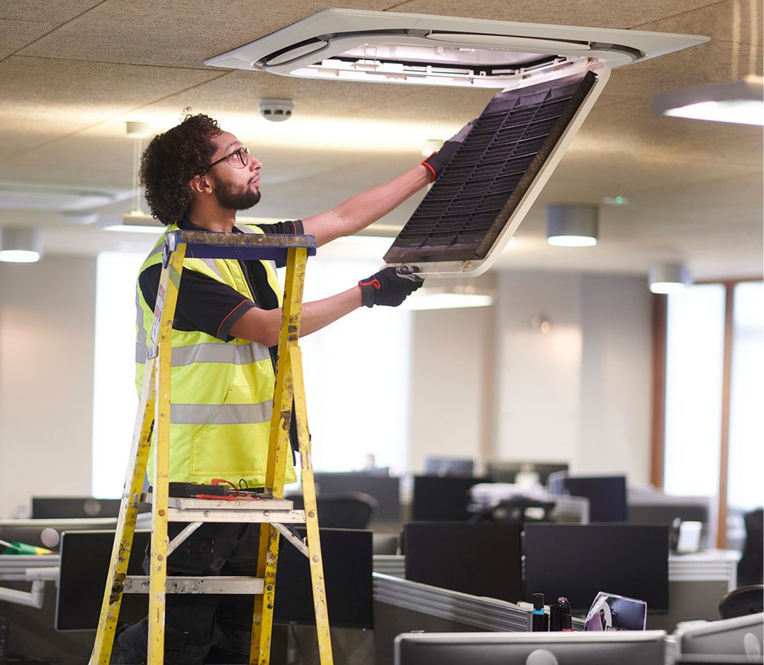 Maintenance worker inspecting ceiling air vent.