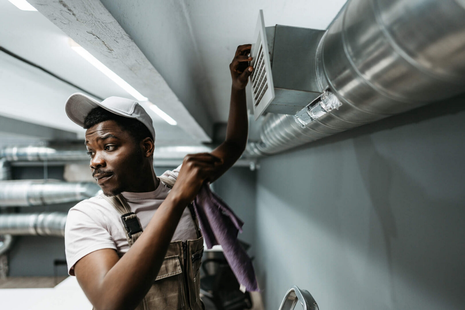 HVAC technician cleaning duct vent in ceiling